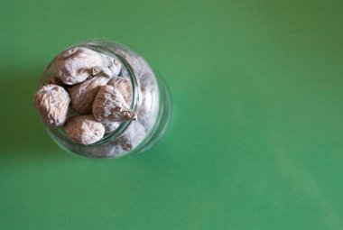 Bardağın üzerine pudra şekeriyle kaplanmış kuru incirler. Yeşil tahta arkaplan