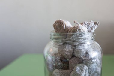 Bardağın üzerine pudra şekeriyle kaplanmış kuru incirler. Yeşil tahta arkaplan