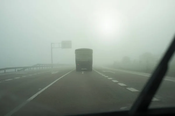 Driving behind a truck under dense fog. Bad-weather driving concept