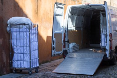 Kirli çamaşır arabaları topluyorum. Asansör rampası ile donatılmış minibüs eski bir kasaba şehrinde park halinde.