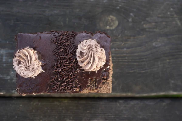 暗い木製の背景の上に3つのチョコレートペストリー クリームの上に 屋外で撃たれた — ストック写真