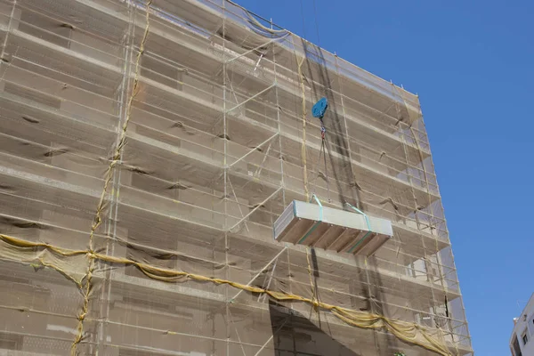 Crane with load of drywall panels over construction site.  Working Under a Suspended Load concept