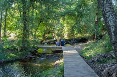 Gevora Nehri, La Codosera, Badajoz, Extremadura, İspanya. Yaşlı çift ahşap köprüde oturuyor.