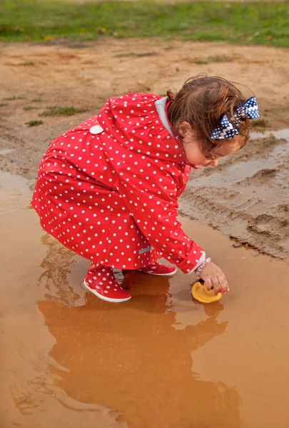 Spelen met haar water speelgoed op muddly plassen — Stockfoto