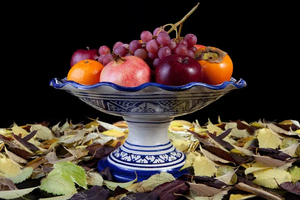 Still life with autumn fruits over dry leaves surface — Stock Photo, Image