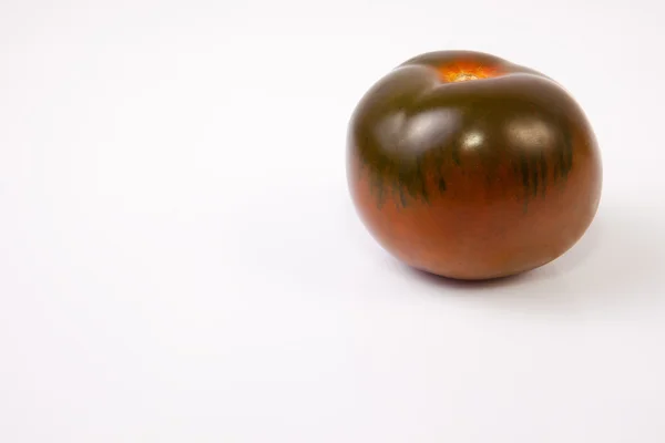 Um tomate kumato verde escuro — Fotografia de Stock