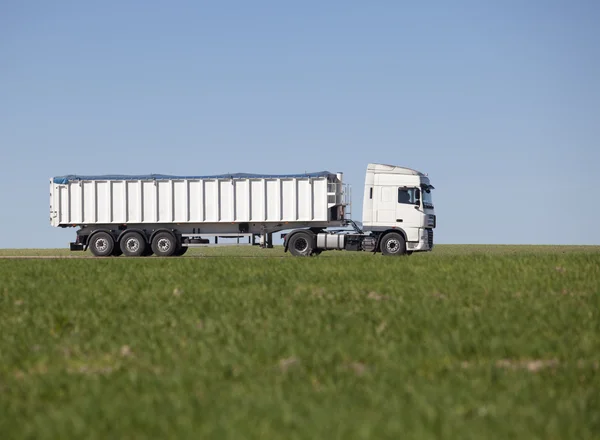 Truck passing by on a green agricultural field — Stock Photo, Image