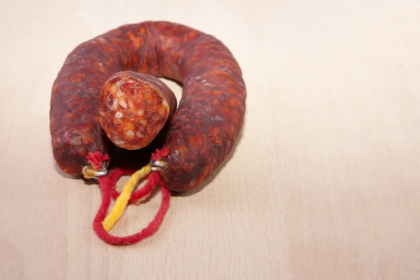 Röd Iberiska chorizo med några skär bitar över träytan — Stockfoto