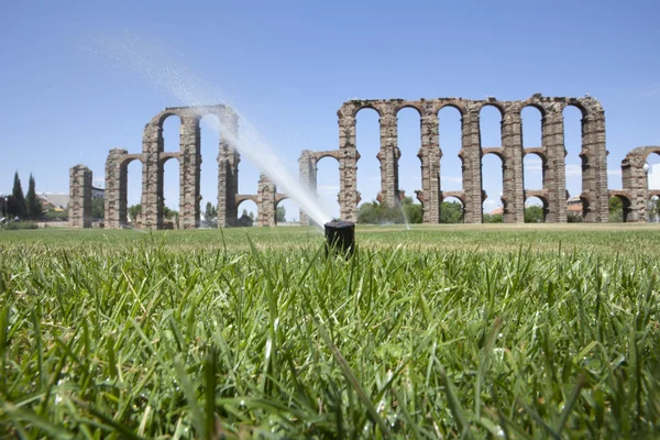 Grass postřikovačů se římský akvadukt — Stock fotografie