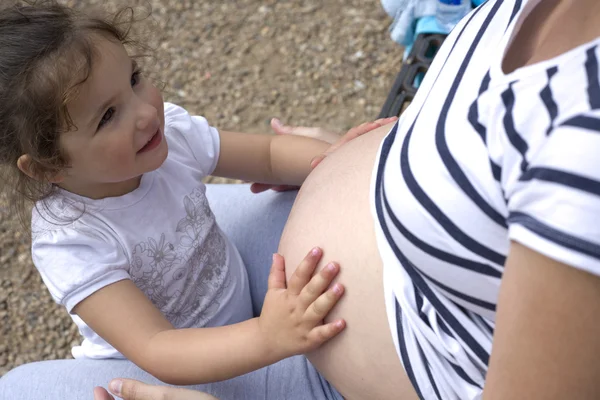 Toddler girl playing with her mother tummy — Stock fotografie