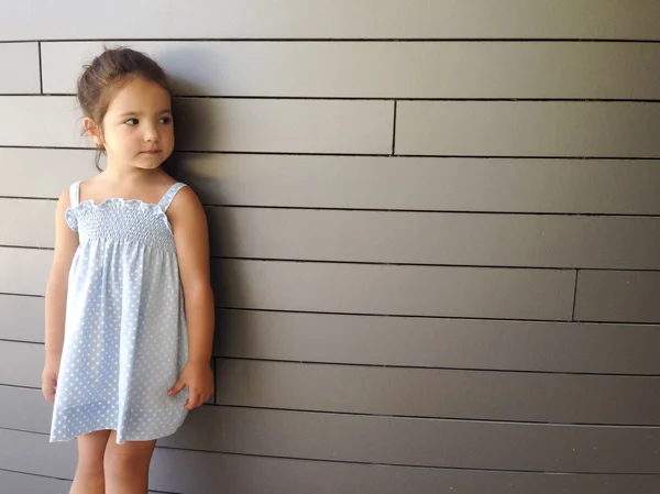 Маленька дівчинка стоїть над сучасною цеглою — стокове фото