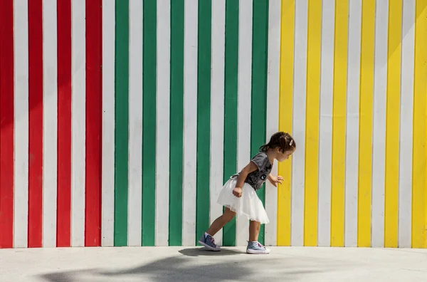 Spielen neben gestreifter farbiger Wand — Stockfoto