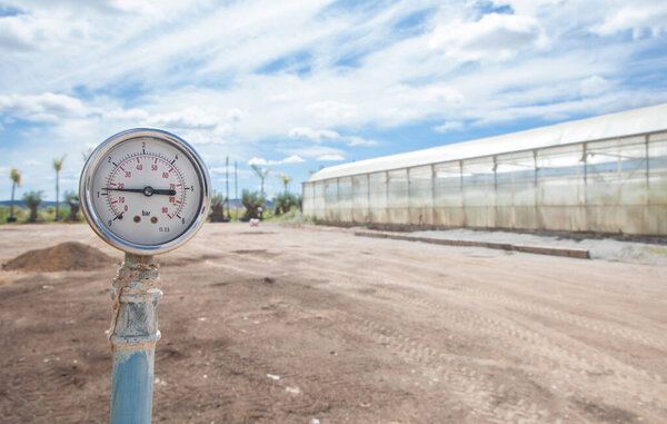 Irrigation system pressure gauge or manometer. Garden center greenhouses at bottom