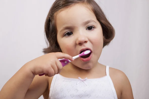 Pequena menina olho marrom escovando os dentes — Fotografia de Stock