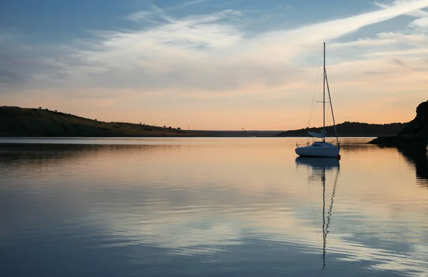 Sunset over Alange Reservoir with anchored sailboat, Spain — Stock Photo, Image