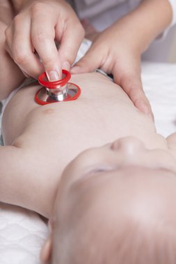 Çocuk doktoru bir stetoskop kullanarak üç ay bebek çocuk inceliyor