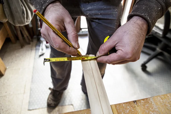 Carpintero midiendo madera y marcando con lápiz — Foto de Stock