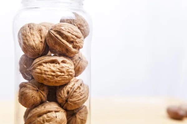 Walnuts on glass jar over wooden surface — Stock Photo, Image