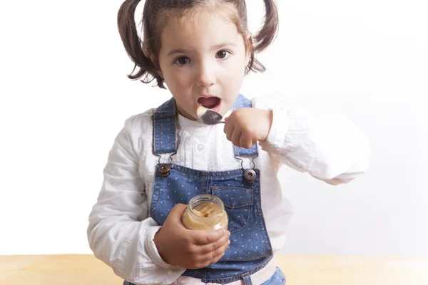 Portrait of happy girl eating a fruit jar of baby food — Stock Photo, Image
