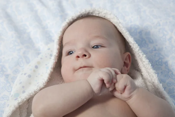 Lindo bebé niño envuelto toalla de baño después del baño en la cama en casa —  Fotos de Stock