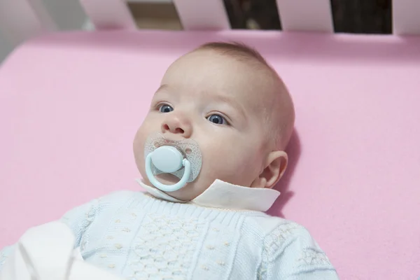 Lindo niño de cuatro meses acostado en una cuna con chupete — Foto de Stock