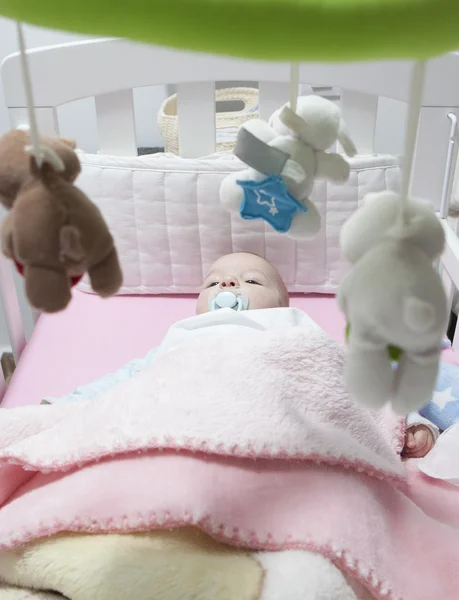 Wakker babyjongen liggen in witte kinderbed met mobile — Stockfoto