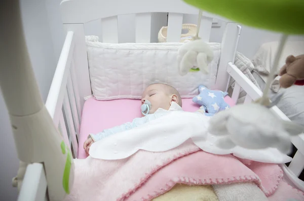 Sleeping four month baby boy lying in cot with mobile — Stock Photo, Image