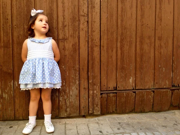 Bambina in piedi sopra la porta di legno intemperie — Foto Stock