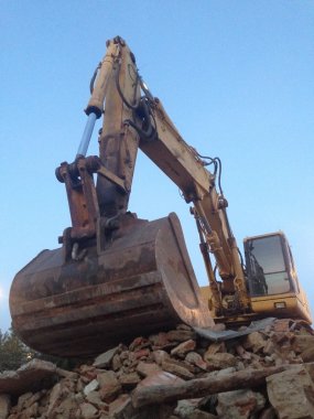 Excavator working over oads of brick rubble debris