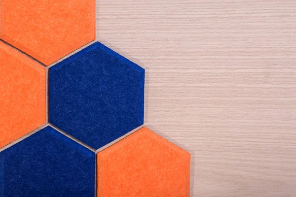 木质纹理背景上橙色和蓝色六边形声学面板 — 图库照片