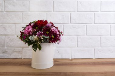 Beyaz tuğlalı bir arka planda vazoda düğün çiçekleri