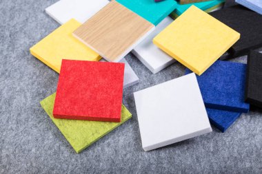 Kırmızı, mavi, sarı, siyah, yeşil ve beyaz renkli akustik polyester paneller gri arkaplanda