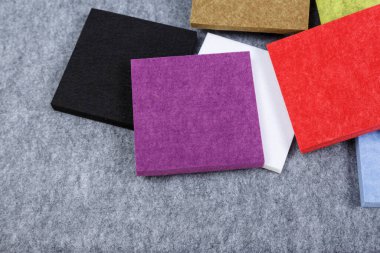 Akustik polyester örnekleri menekşe, kırmızı, beyaz, siyah, yeşil. Gri arkaplanda mavi renkler