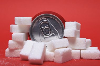 cola refreshing drink can and lot of white sugar cubes representing the big amount of calories