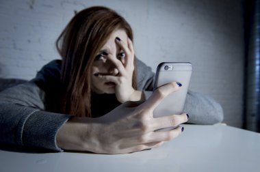 young sad vulnerable girl using mobile phone scared and desperate suffering online abuse cyberbullying