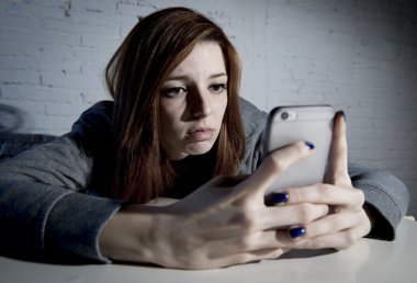 young sad vulnerable girl using mobile phone scared and desperate suffering online abuse cyberbullying