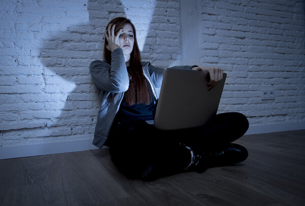 scared female teenager with computer laptop suffering cyberbullying and harassment being online abused