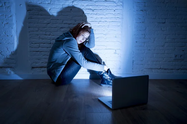 Scared female teenager with computer laptop suffering cyberbullying and harassment being online abused — Stock Photo, Image