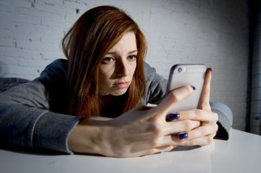 young sad vulnerable girl using mobile phone scared and desperate suffering online abuse cyberbullying