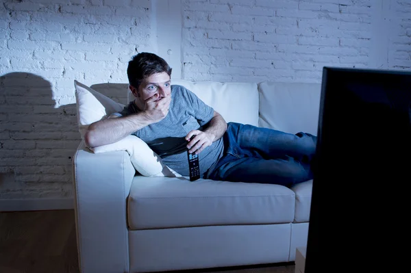 Attrayant homme à la maison couché sur le canapé au salon regarder la télévision à la recherche surpris en état de choc — Photo