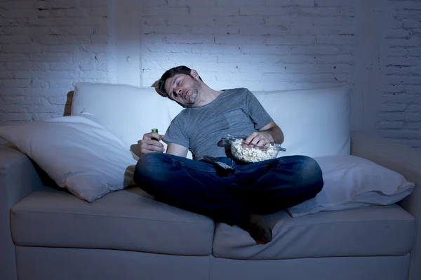 Joven en casa sofá en la sala de estar durmiendo mientras ve la película o el deporte en la televisión por la noche — Foto de Stock