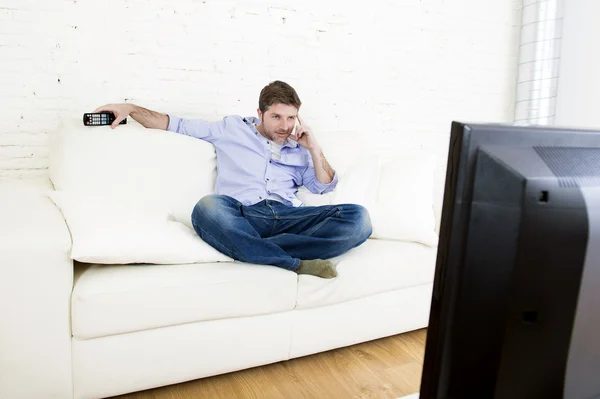 Jovem homem feliz assistindo tv sentado em casa sala de estar sofá olhando relaxado desfrutando de televisão — Fotografia de Stock