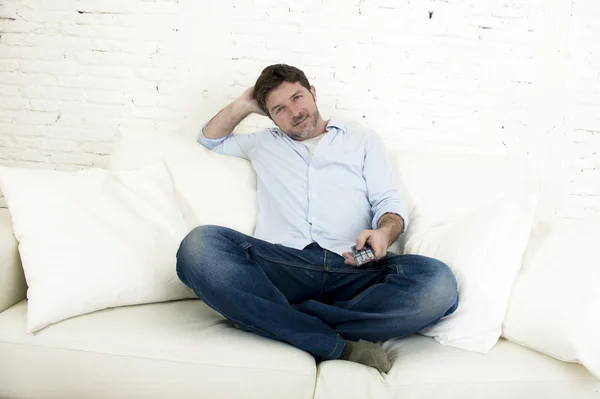 Young happy man watching tv sitting at home living room sofa looking relaxed enjoying television — Stock Photo, Image