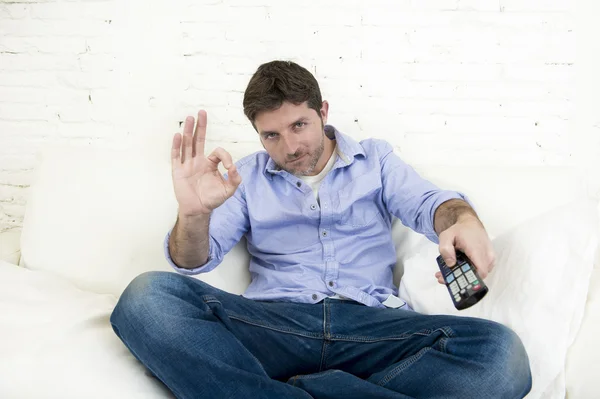 Homme regardant la télévision au salon canapé avec télécommande souriant donnant signe de la main OK — Photo