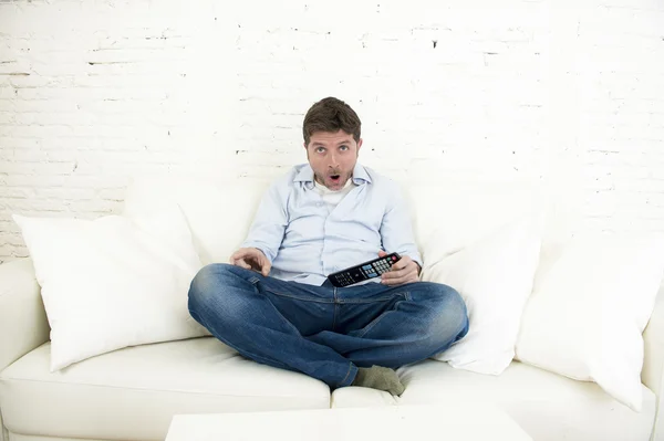 Hombre viendo la televisión en casa sala de estar sofá con control remoto mirando muy interesado —  Fotos de Stock