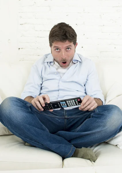 Hombre viendo la televisión en casa sala de estar sofá con control remoto mirando muy interesado —  Fotos de Stock