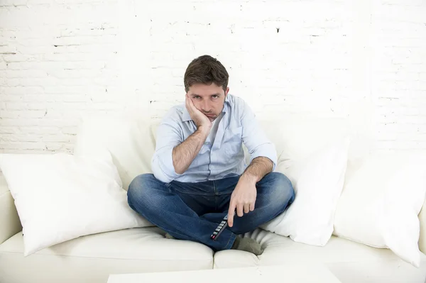 Homme ennuyé regarder la télévision assis sur le canapé tenant la télécommande fatigué de ne pas s'amuser — Photo