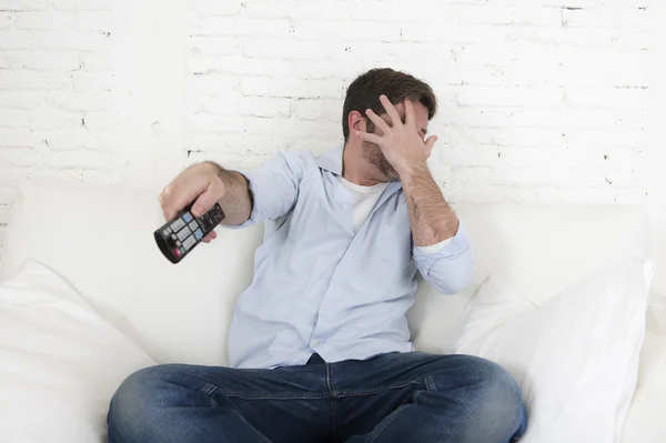 Gelukkig jongeman die betrekking hebben op zijn ogen, bang en geschokt horrorfilm van de televisie kijken — Stockfoto