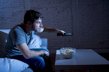 televizyon bağımlısı adam uzaktan kumanda kullanarak patlamış mısır yeme Tv izlerken ev kanepede oturan