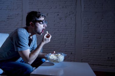  kanepede televizyon bağımlısı adam Tv izlerken ve komik nerd geek gözlük patlamış mısır yeme